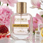 Perfume bottle labeled 'Lobster Miami Beach' with pink flowers and pomegranates in the background