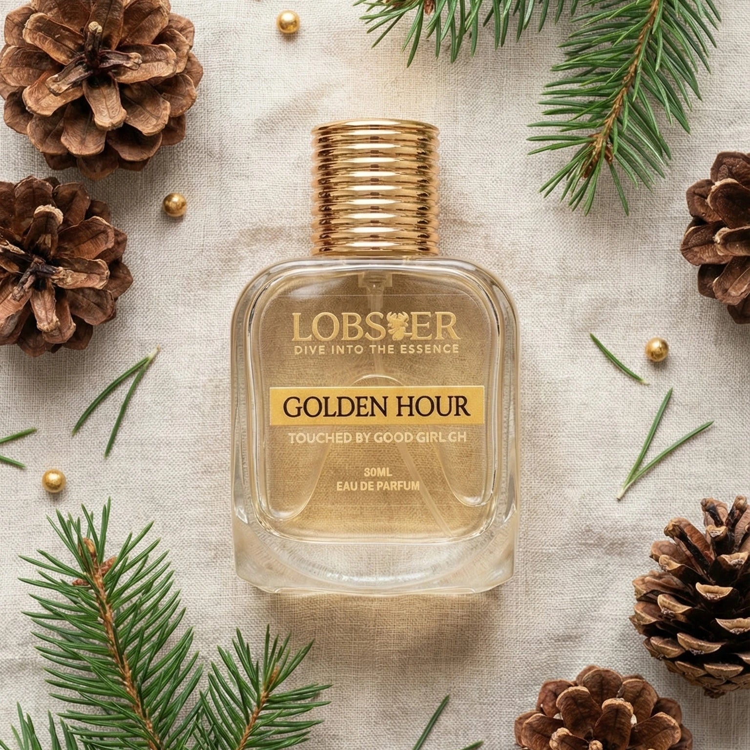 Lobster Golden Hour perfume bottle surrounded by pine cones and branches on a textured surface