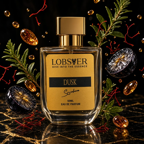 A perfume bottle labeled LOBSER DUSK Eau de Parfum, featuring a gold cap and a gold label with black text, set on a black marble surface with gold veins. The bottle is surrounded by decorative green pine branches, dark berries, and floating amber droplets against a dark background.