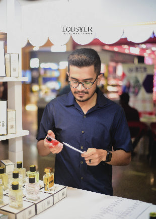 Man examining a bottle of perfume in a store with 'LOBSTER' branding.